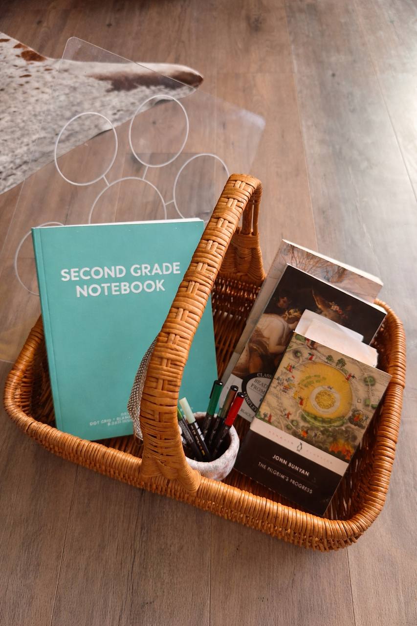 Second grade homeschool basket with notebook, pens, and books