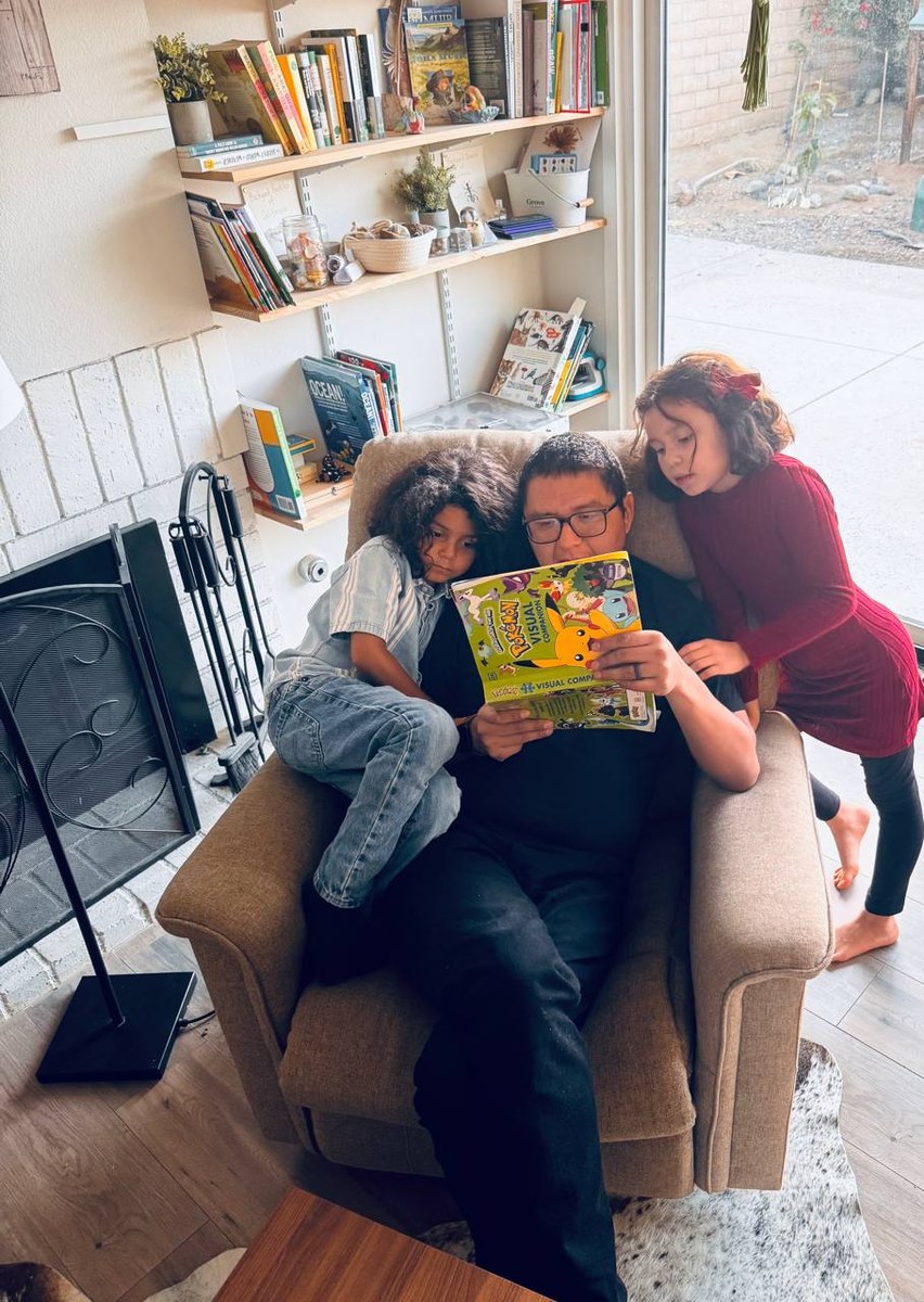 A family reading together in a cozy chair by the bookshelf