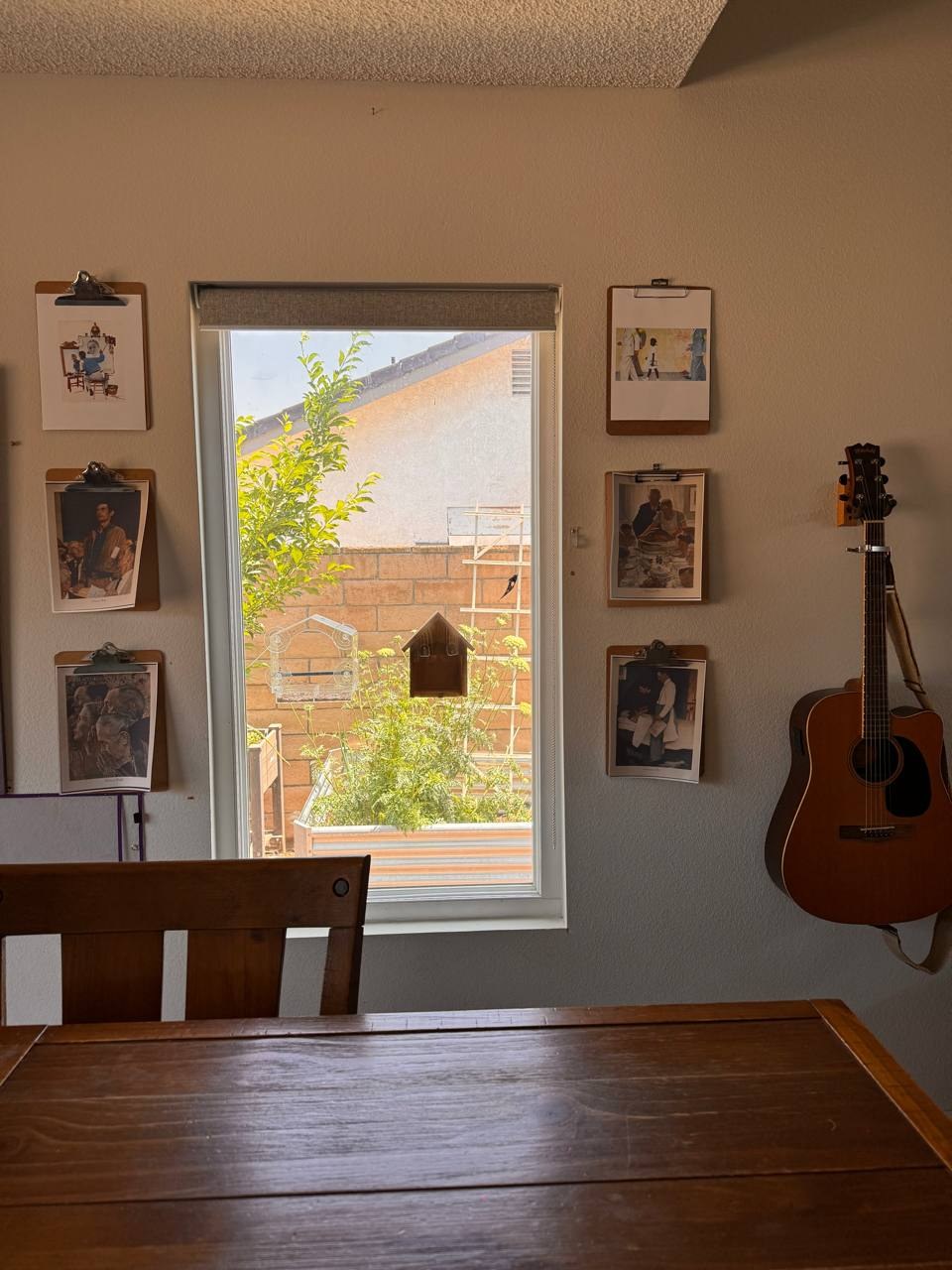 Artist picture-study prints displayed on clipboards around a dining room window where homeschool lessons are done