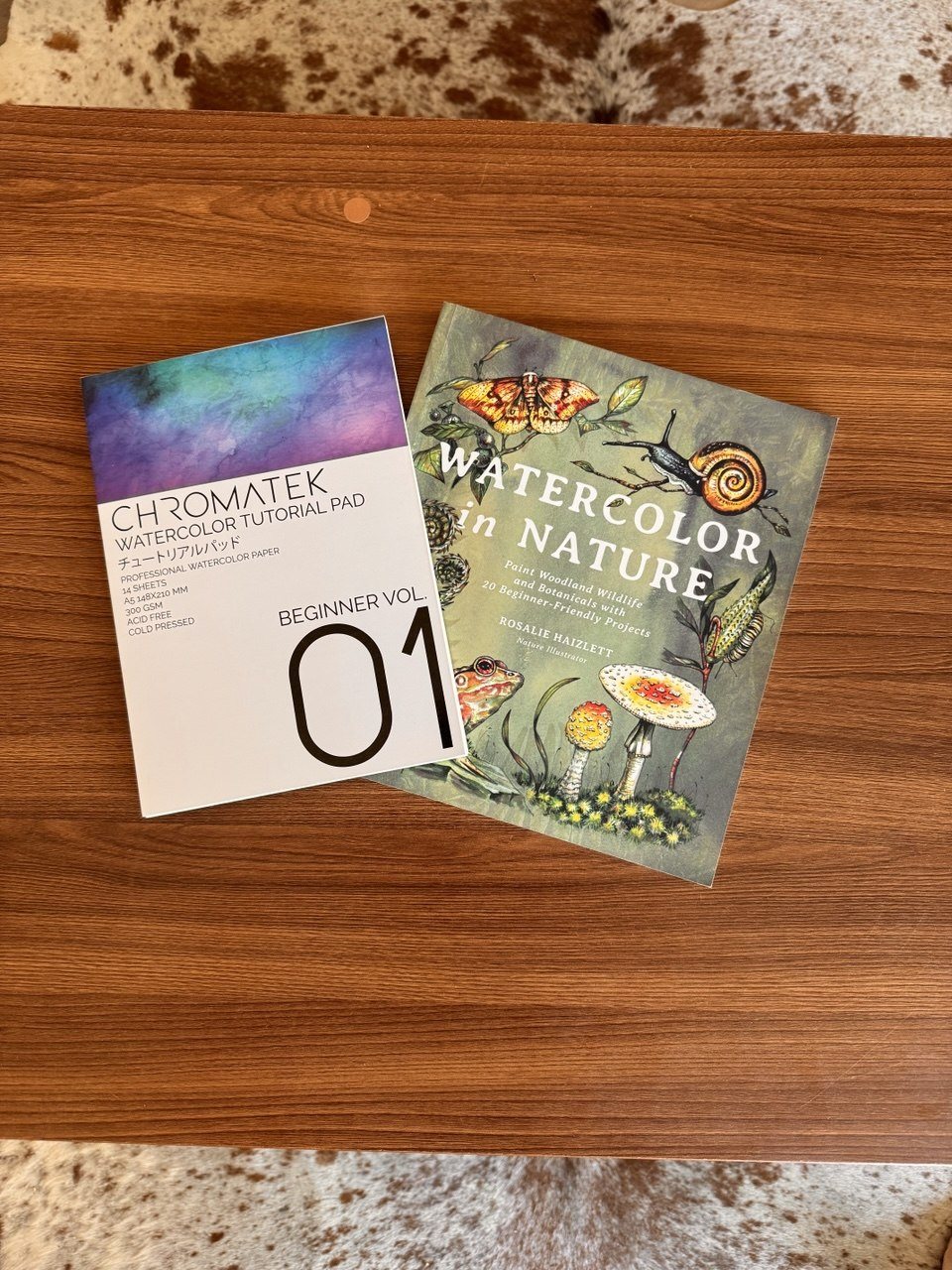 Watercolor in Nature and a Chromatek watercolor tutorial pad arranged on a wooden table
